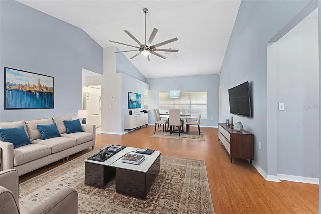 A living and dining room with vaulted ceilings, light blue walls, and hardwood flooring — 1031 ALMONDWOOD DRIVE, TRINITY, FL
