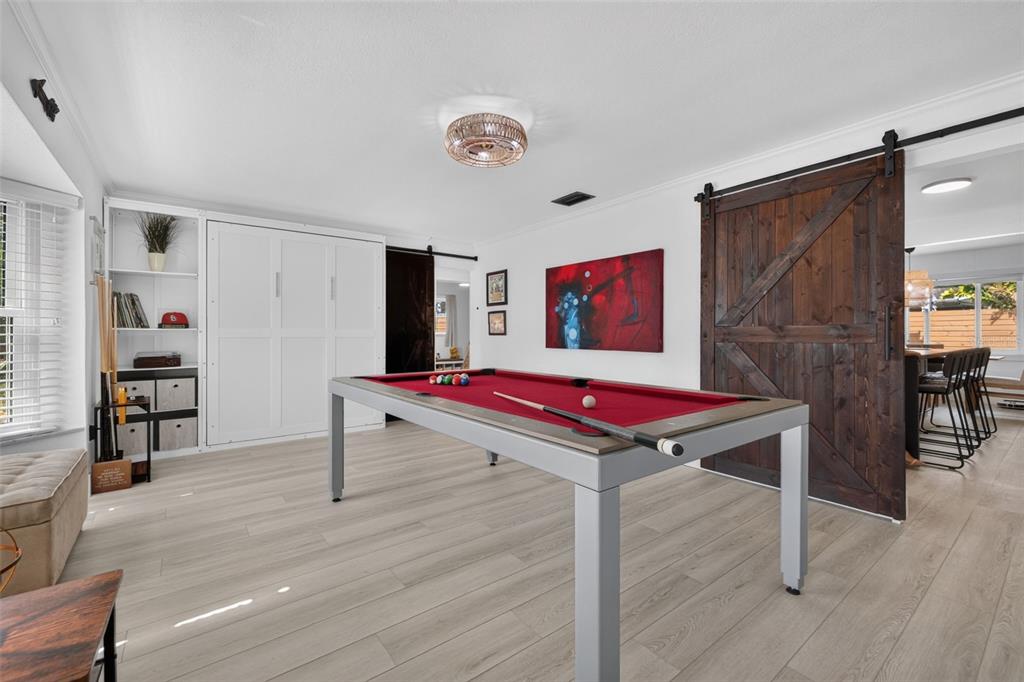 A game room features a red pool table, light wood flooring, and a large barn door — 7566 20TH STREET N, ST PETERSBURG, FL