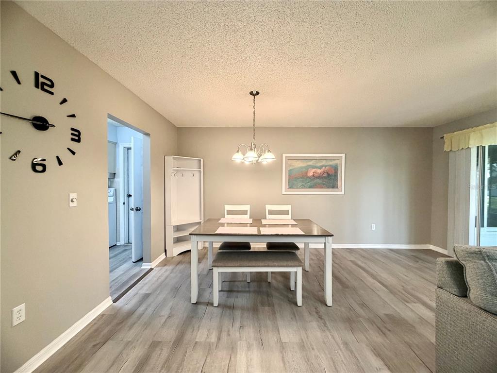 An open-concept living and dining area features light wood-look flooring and neutral gray walls — 17929 SE 105TH AVENUE, SUMMERFIELD, FL
