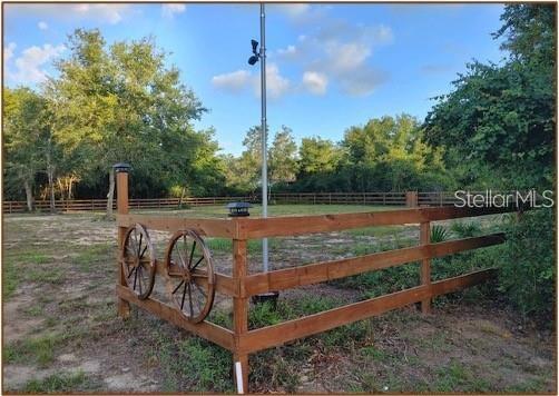 A wooden fence with decorative wagon wheels surrounds a grassy yard with a tall pole — NE 135TH STREET, SALT SPRINGS, FL
