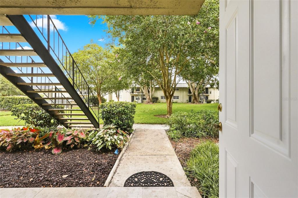 A view from an open doorway looking out onto a concrete walkway and grassy courtyard — 525 CONWAY ROAD UNIT 29, ORLANDO, FL