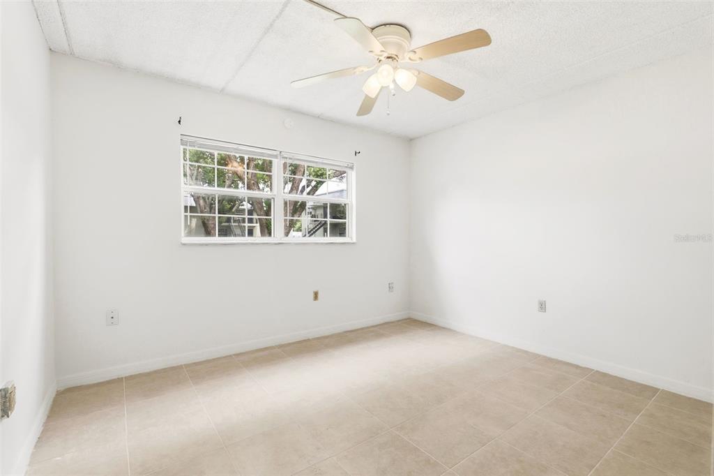An empty bedroom features white walls, a ceiling fan, a window, and light-colored tile flooring — 525 CONWAY ROAD UNIT 29, ORLANDO, FL