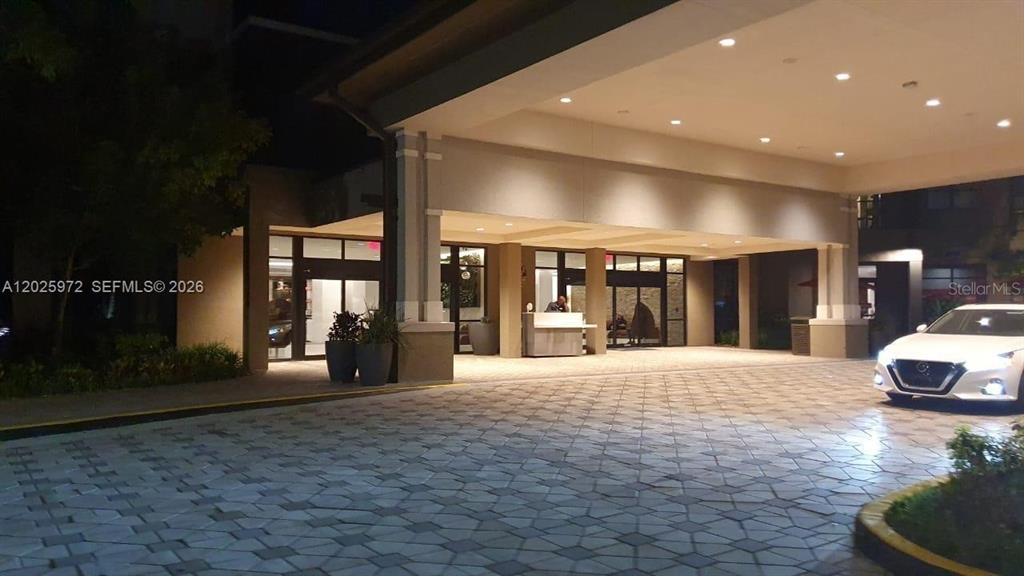 A paved driveway leads to the covered entrance of a modern building at night — 14501 GROVE RESORT AVENUE UNIT 3425, WINTER GARDEN, FL