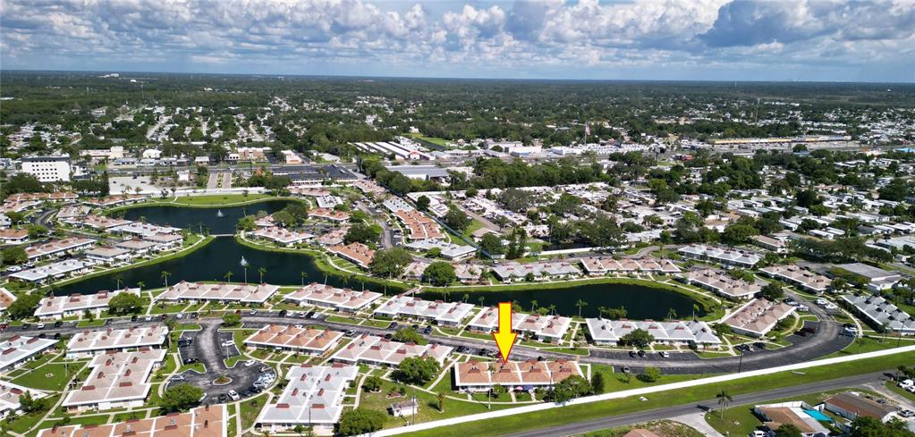 An aerial view shows a residential complex with multiple buildings, ponds, and a yellow arrow — 4337 TAHITIAN GARDENS CIRCLE UNIT F, HOLIDAY, FL
