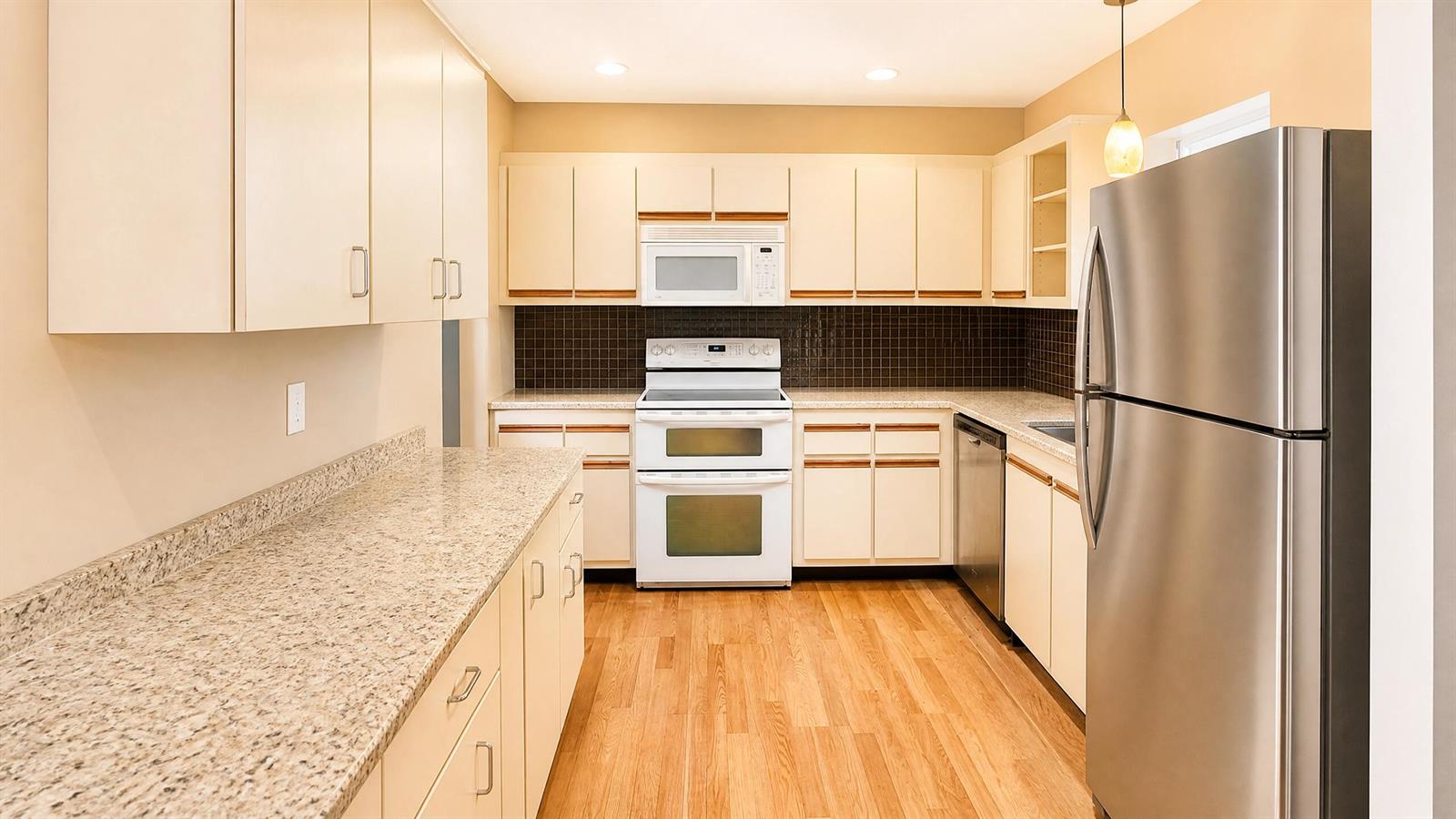 A kitchen with white cabinets, granite countertops, stainless steel appliances, and wood-look flooring — 3575 NW 94th Avenue # 8d, Sunrise FL 33351, SUNRISE, FL