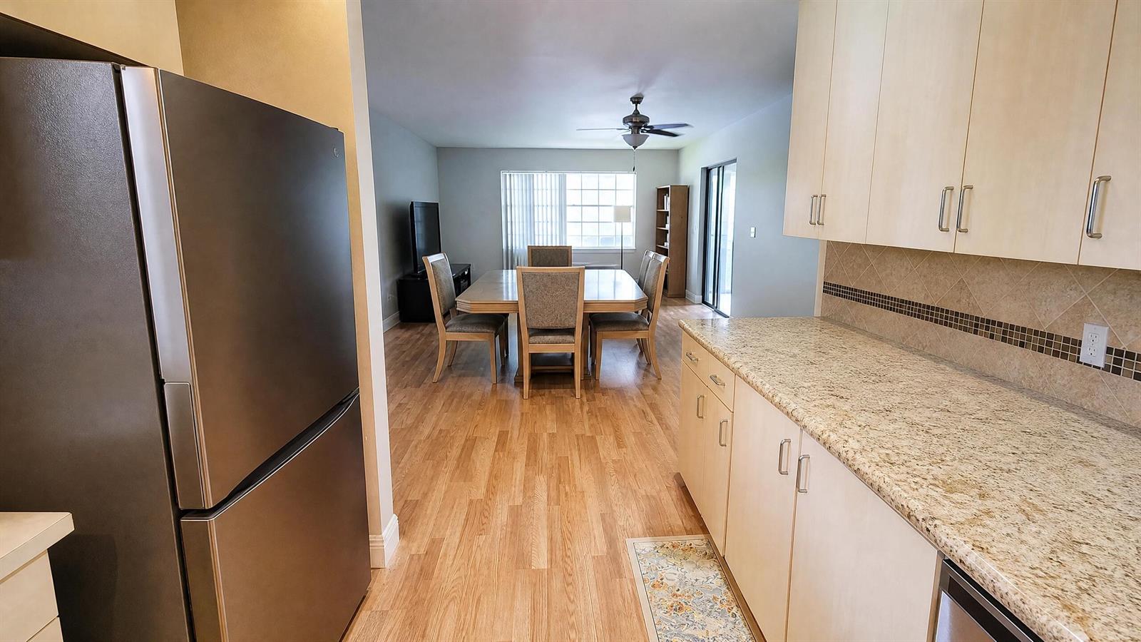 A kitchen with light cabinets and granite countertops opens into a dining area with wood flooring — 3575 NW 94th Avenue # 8d, Sunrise FL 33351, SUNRISE, FL