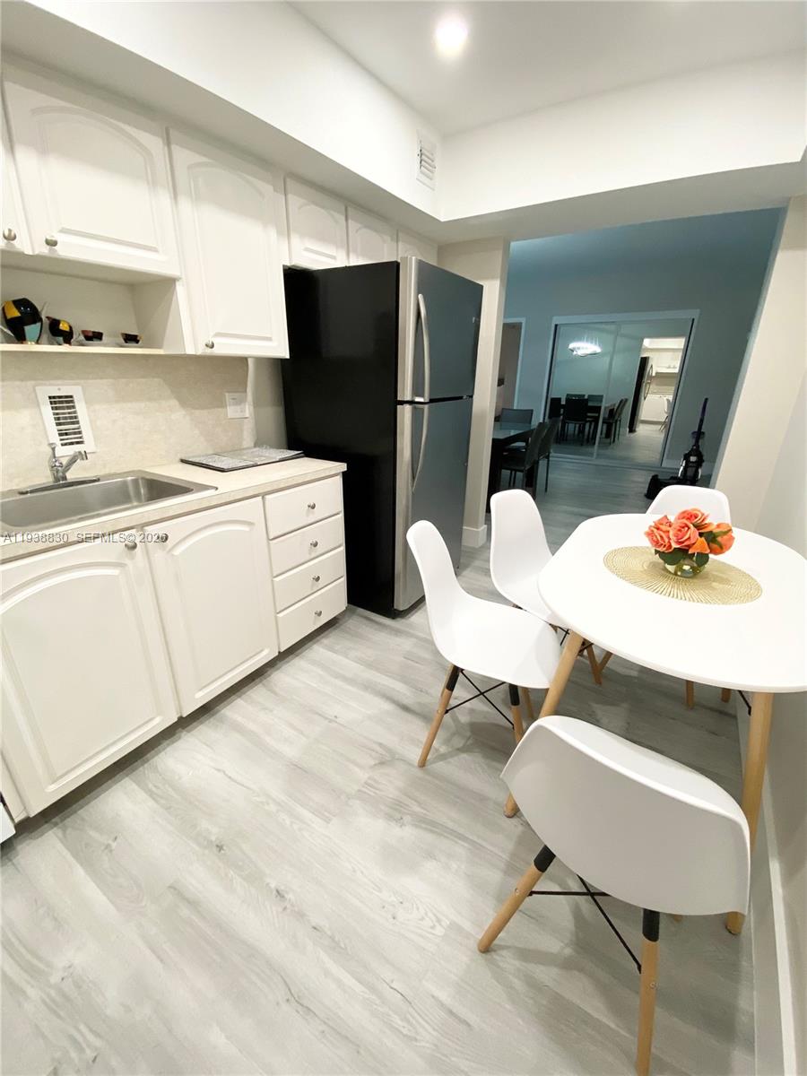 A kitchen features white cabinets, a black refrigerator, and a small dining table with chairs — 4001 S Ocean Dr # 4M, Hollywood FL 33019, HOLLYWOOD, FL