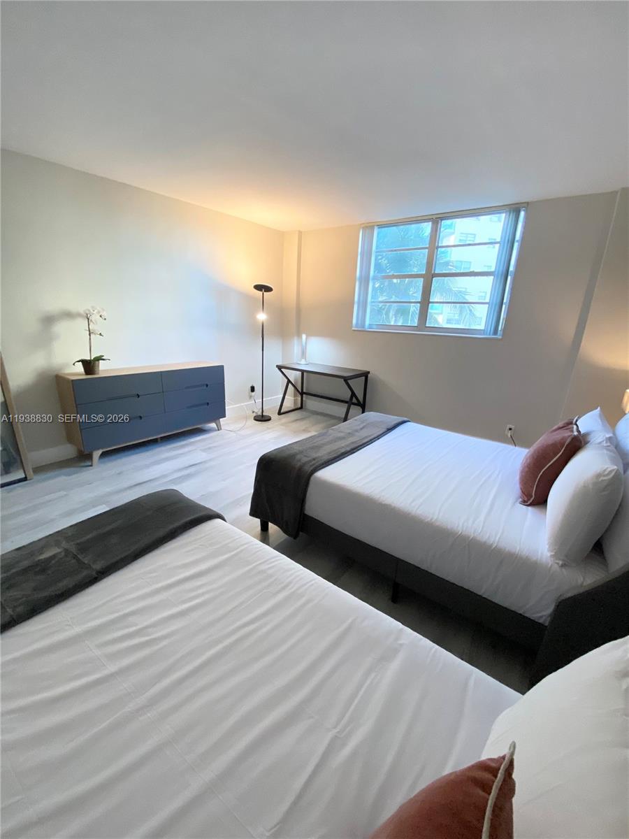 A bedroom features two beds, a dresser, a desk, and a window with light flooring — 4001 S Ocean Dr # 4M, Hollywood FL 33019, HOLLYWOOD, FL