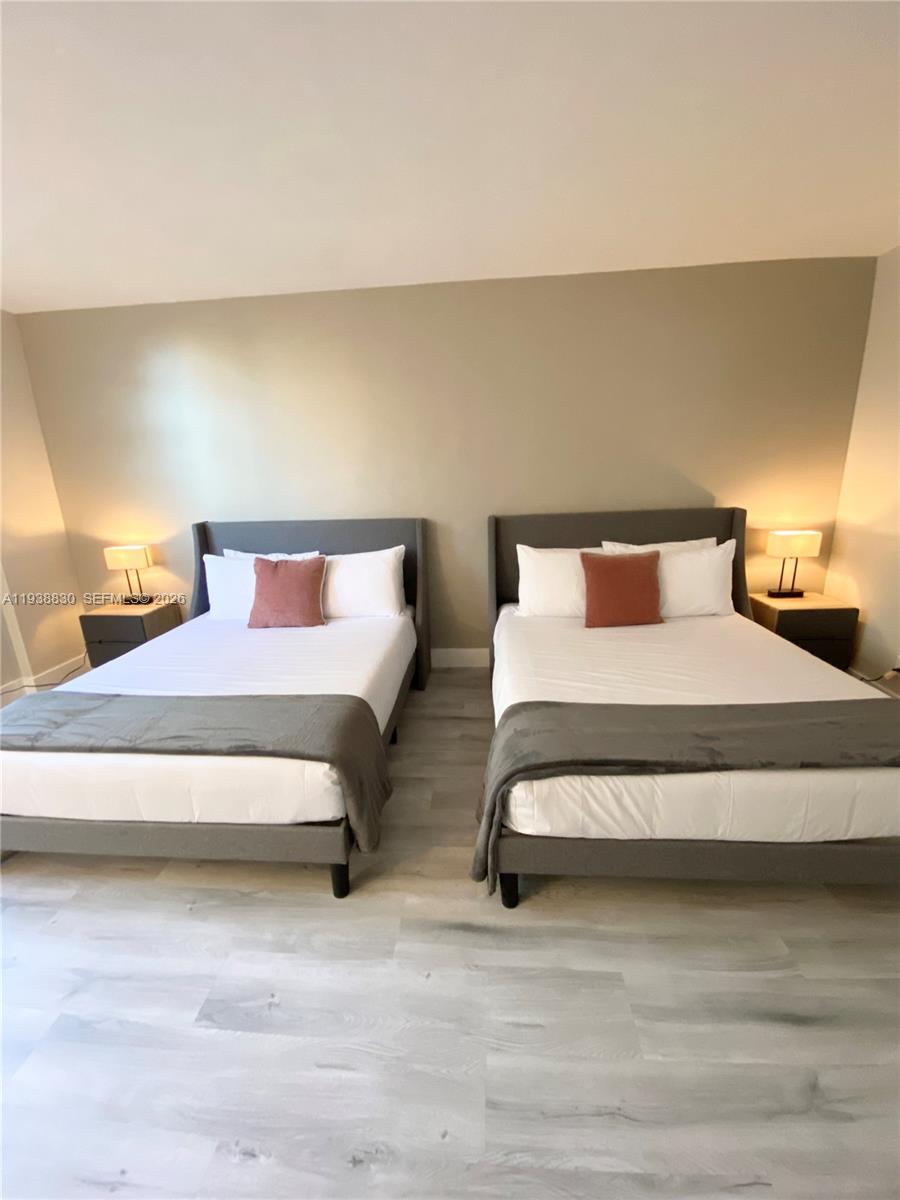 A bedroom features two gray upholstered beds with white bedding and light wood flooring — 4001 S Ocean Dr # 4M, Hollywood FL 33019, HOLLYWOOD, FL
