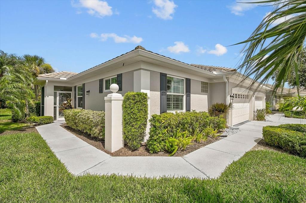 A single-story house with a beige stucco exterior, a tiled roof, and a concrete walkway — 1631 MONARCH DRIVE UNIT 1631, VENICE, FL