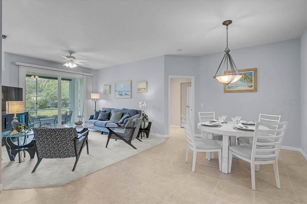 An open-concept living and dining area features tile flooring, a ceiling fan, and sliding doors — 1631 MONARCH DRIVE UNIT 1631, VENICE, FL