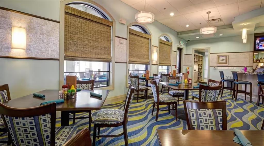 A restaurant dining room features wooden tables, patterned chairs, and large windows with bamboo shades — 1836 NICE COURT, KISSIMMEE, FL
