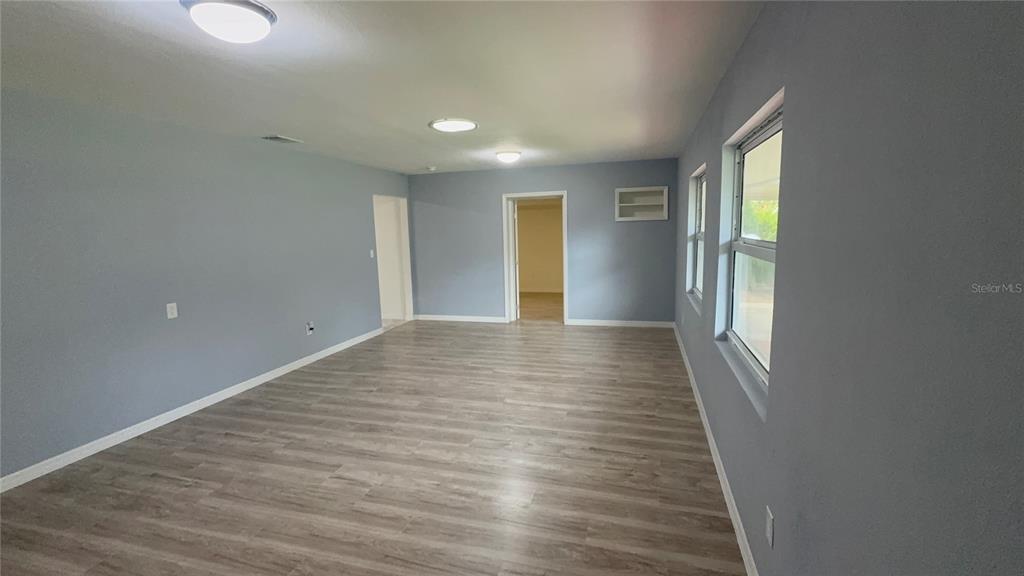 An empty room features light gray walls, wood-look flooring, recessed lighting, and two windows — 2218 AVENUE B SW, WINTER HAVEN, FL
