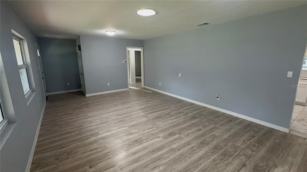 An empty living room features light gray walls, wood-look flooring, and two ceiling light fixtures — 2218 AVENUE B SW, WINTER HAVEN, FL