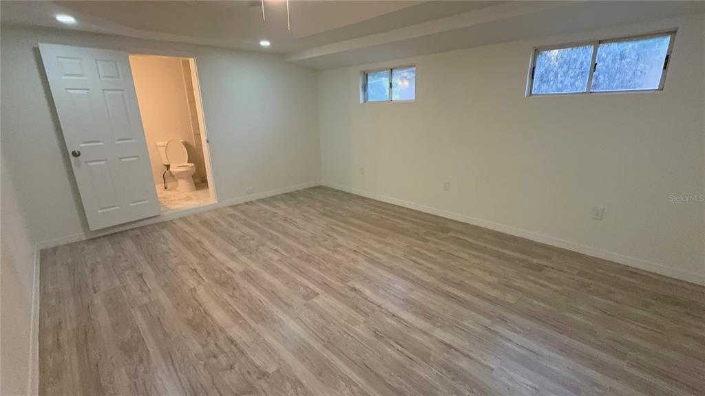 A room with light wood-look flooring, white walls, two small windows, and an attached bathroom — 2218 AVENUE B SW, WINTER HAVEN, FL