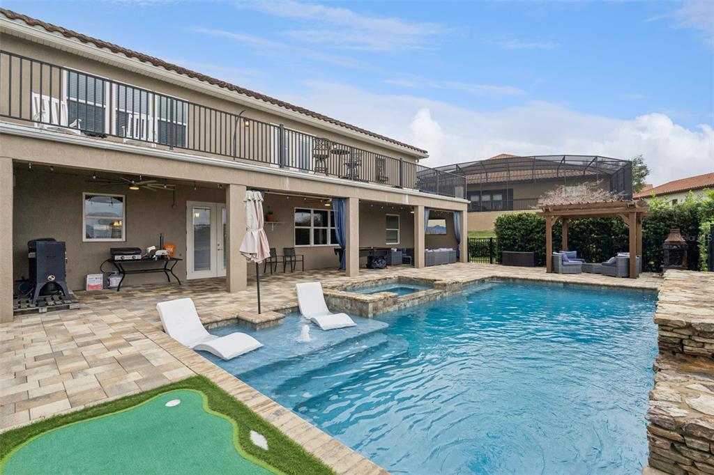 A backyard patio features a swimming pool with lounge chairs, a spa, and a pergola — 1784 BELLA LAGO DRIVE, CLERMONT, FL