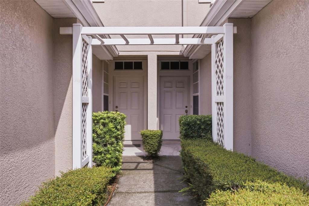 A concrete walkway leads to two front doors framed by a white wooden trellis — 4132 BISMARCK PALM DRIVE, TAMPA, FL