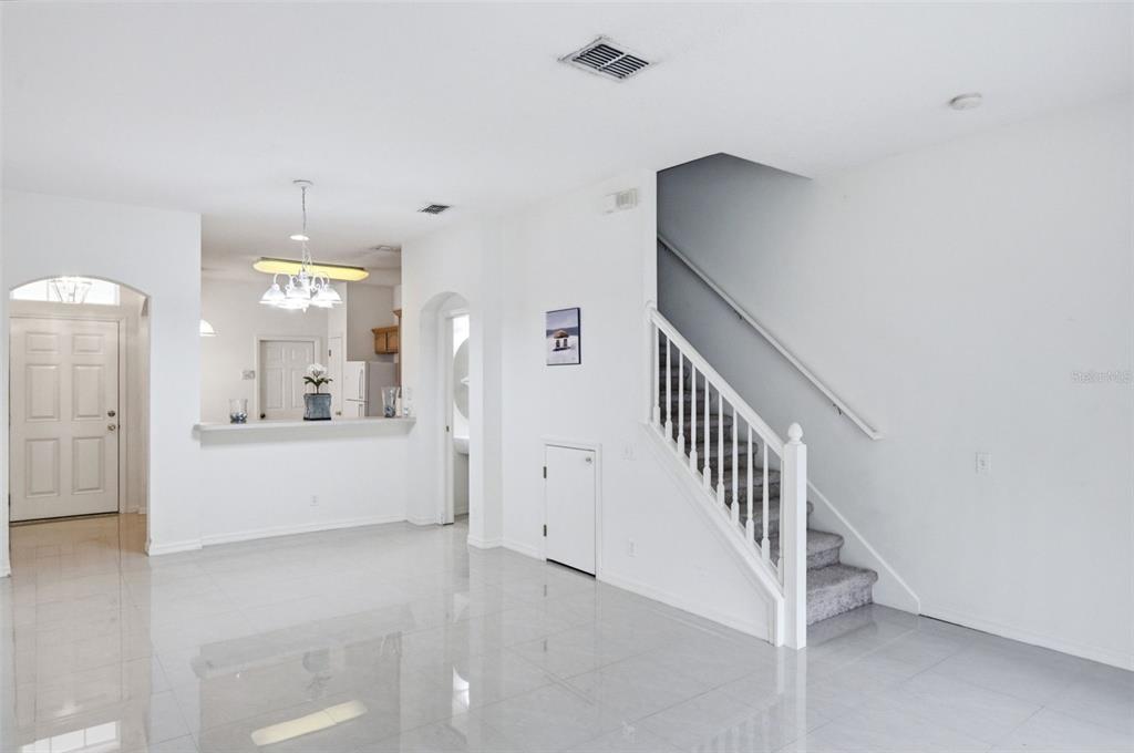 An interior view of a living area with white walls, tile flooring, and a staircase — 4132 BISMARCK PALM DRIVE, TAMPA, FL