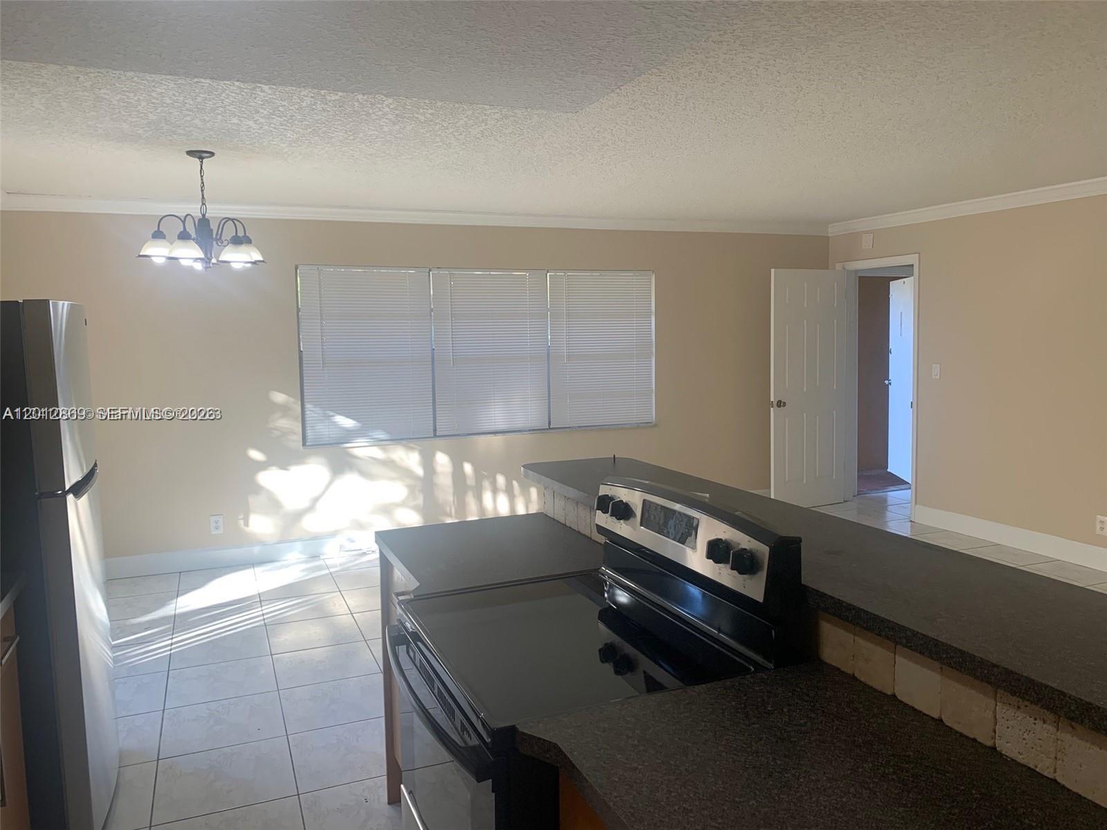 A kitchen features a black stove, dark countertops, tile flooring, and a dining area window — 1702 Mckinley St # 4, Hollywood FL 33020, HOLLYWOOD, FL
