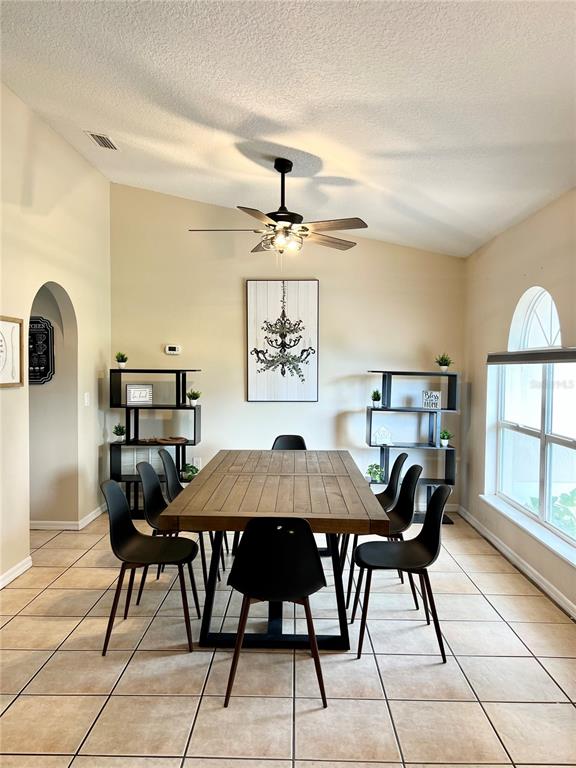 A dining room features a wooden table, black chairs, two shelving units, and a ceiling fan — 331 MARQUEE DRIVE, KISSIMMEE, FL