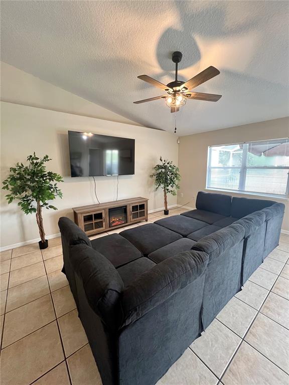 A living room features a large sectional sofa, a wall-mounted television, and a ceiling fan — 331 MARQUEE DRIVE, KISSIMMEE, FL