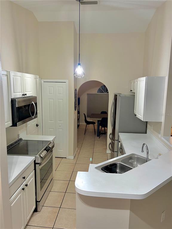 A kitchen with white cabinets, stainless steel appliances, and a peninsula sink overlooks a dining area — 331 MARQUEE DRIVE, KISSIMMEE, FL
