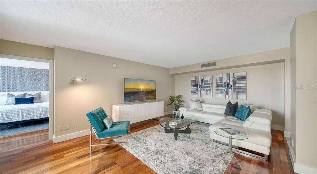 A living room features a white sectional sofa, a teal armchair, and hardwood floors — 1111 N GULFSTREAM AVENUE UNIT 4E, SARASOTA, FL