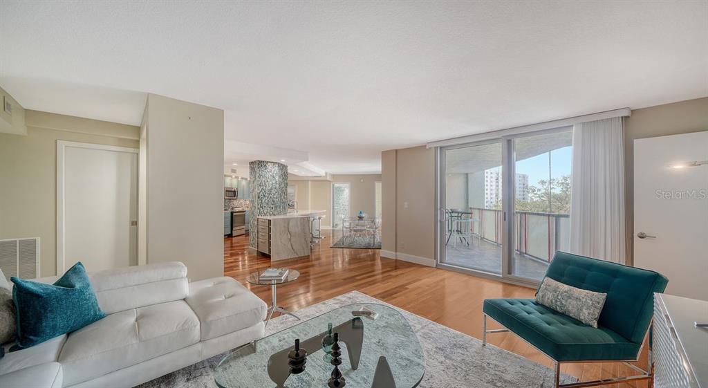 A living room with hardwood floors, a white sofa, a teal chair, and a balcony — 1111 N GULFSTREAM AVENUE UNIT 4E, SARASOTA, FL