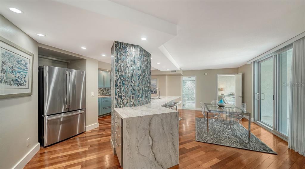 A kitchen and dining area with marble countertops, a tiled pillar, and hardwood flooring — 1111 N GULFSTREAM AVENUE UNIT 4E, SARASOTA, FL