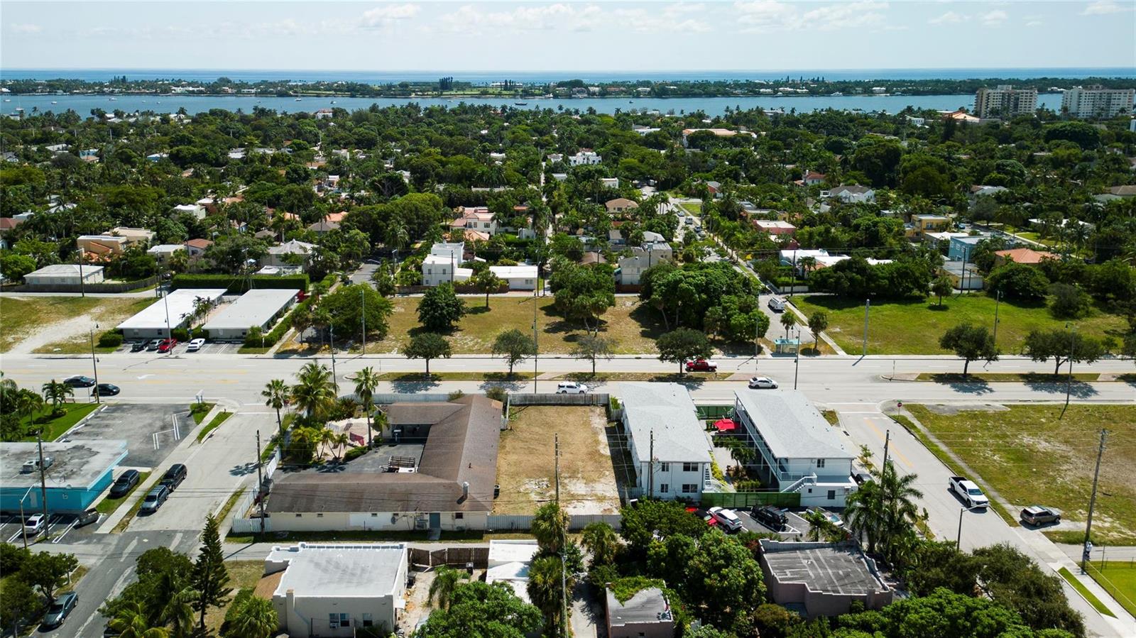 An aerial view shows a residential neighborhood with several buildings, vacant lots, and palm trees — Broadway, West Palm Beach FL 33407, WEST PALM BEACH, FL