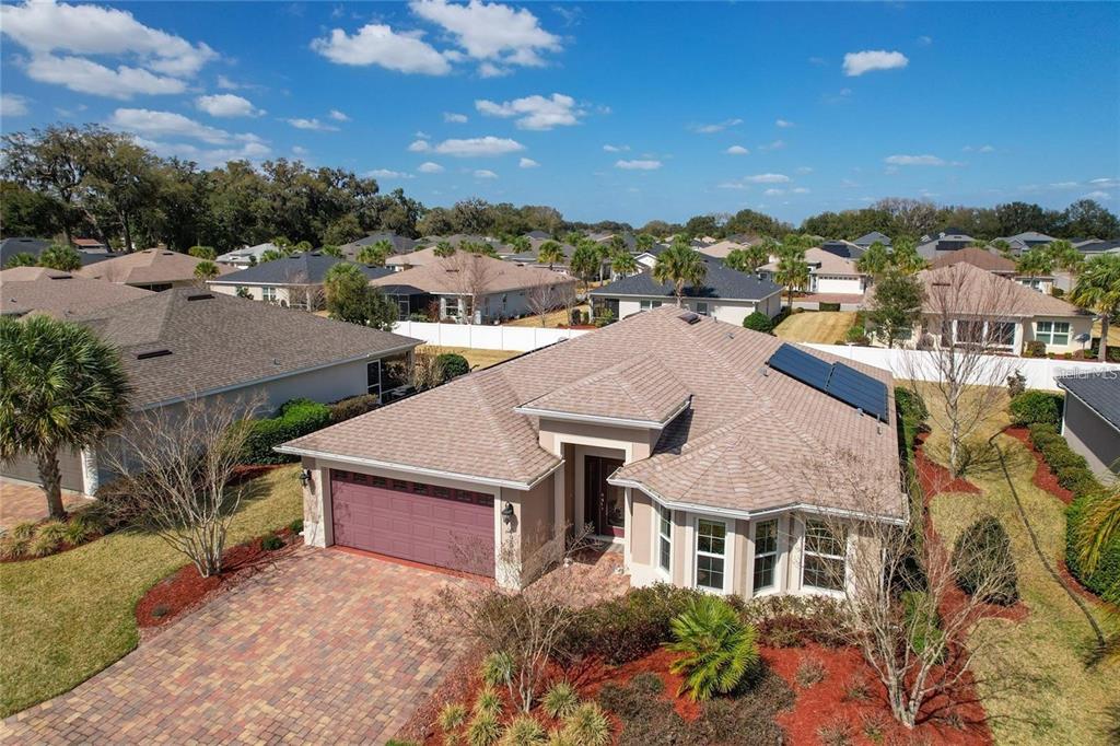 An aerial view of a single-story suburban house with a brick driveway and solar panels — 4992 SANDPIPER DRIVE, OXFORD, FL