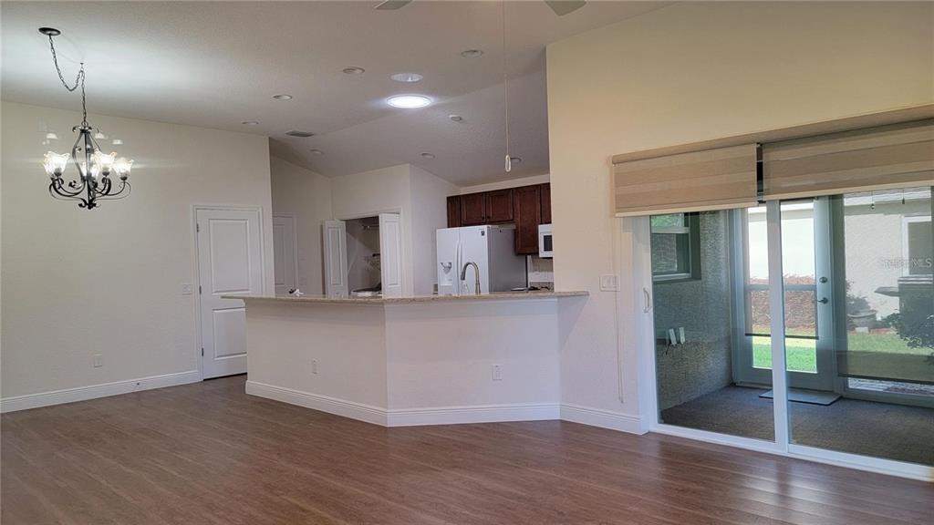 An open-concept kitchen with a breakfast bar overlooks a living area with sliding glass doors — 4992 SANDPIPER DRIVE, OXFORD, FL