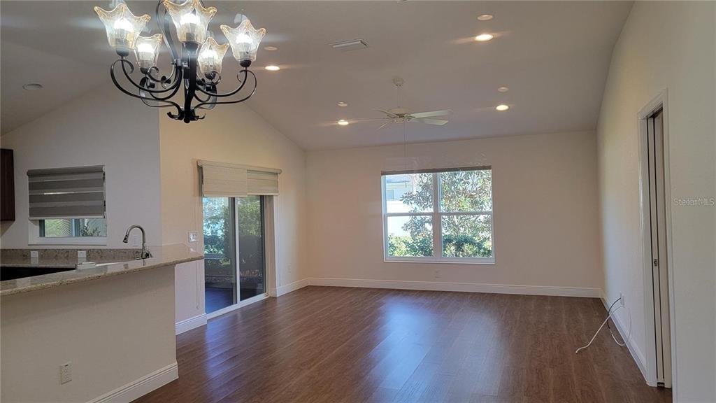 An open-concept living area features wood-look flooring, a vaulted ceiling, and a chandelier — 4992 SANDPIPER DRIVE, OXFORD, FL