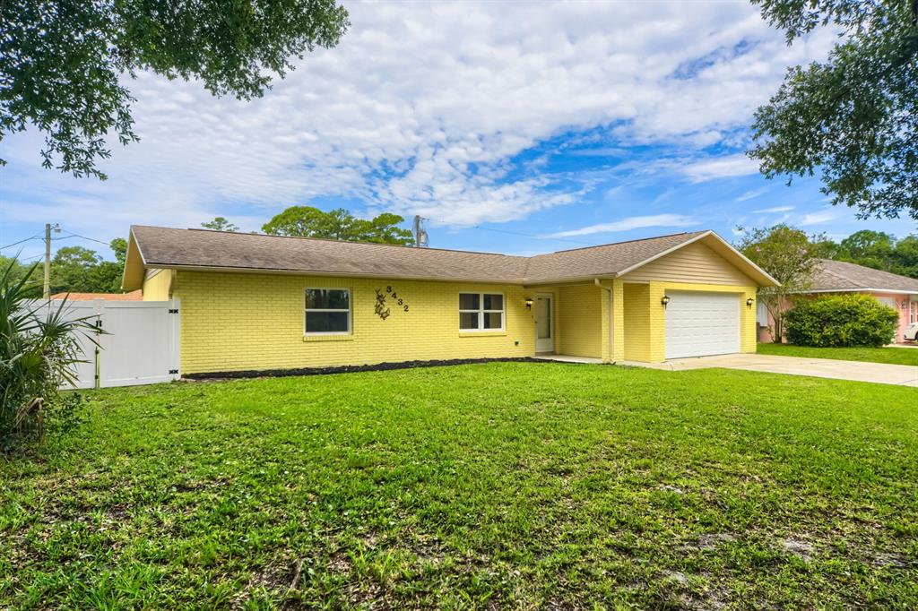 A yellow brick, single-story house with a white garage door and a white privacy fence — 3432 UNITY TREE DRIVE, EDGEWATER, FL