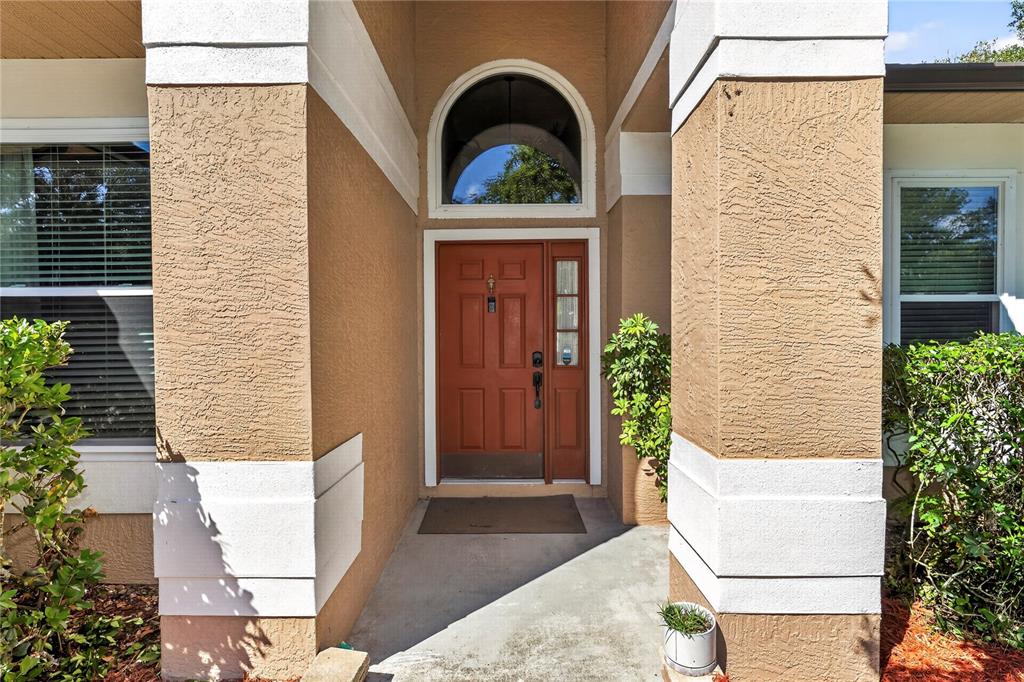 The exterior view shows a tan stucco home entrance with a red front door — 1907 WESTBOURNE DRIVE, OVIEDO, FL