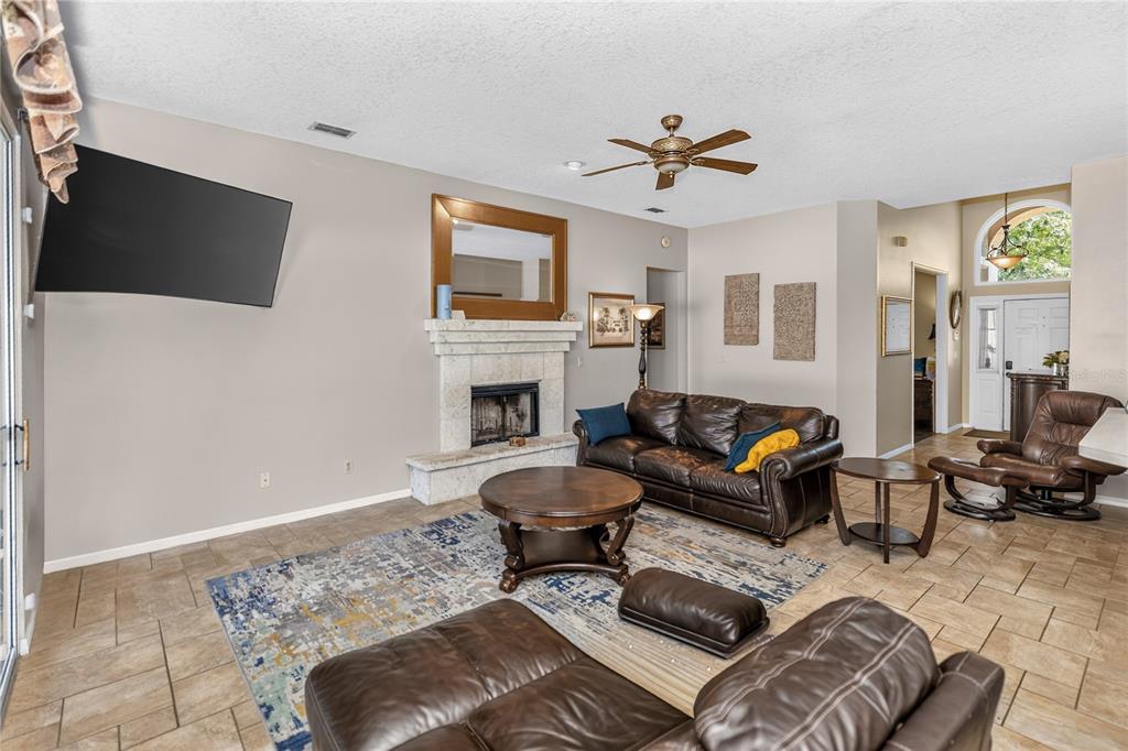 A living room features a fireplace, leather furniture, tile flooring, and a ceiling fan — 1907 WESTBOURNE DRIVE, OVIEDO, FL