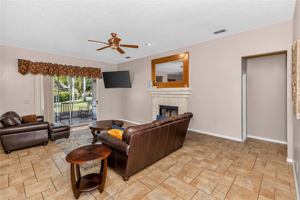 A living room features tile flooring, a fireplace, a ceiling fan, and a sliding glass door — 1907 WESTBOURNE DRIVE, OVIEDO, FL