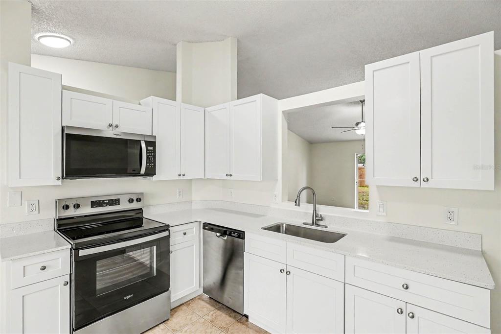 A kitchen with white cabinets, stainless steel appliances, and light-colored countertops — 1142 JASLO STREET SE, PALM BAY, FL