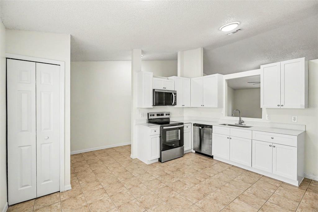 A kitchen with white cabinets, stainless steel appliances, and light-colored tile flooring — 1142 JASLO STREET SE, PALM BAY, FL
