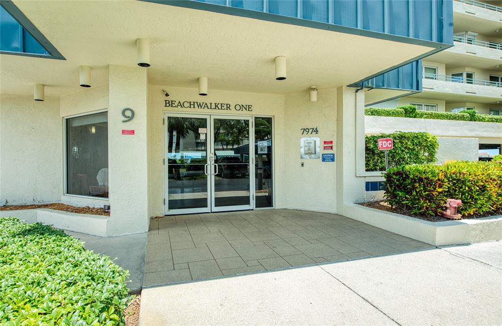 The exterior entrance of a building features glass double doors under a covered walkway — 7974 SAILBOAT KEY BOULEVARD S UNIT 301, SOUTH PASADENA, FL