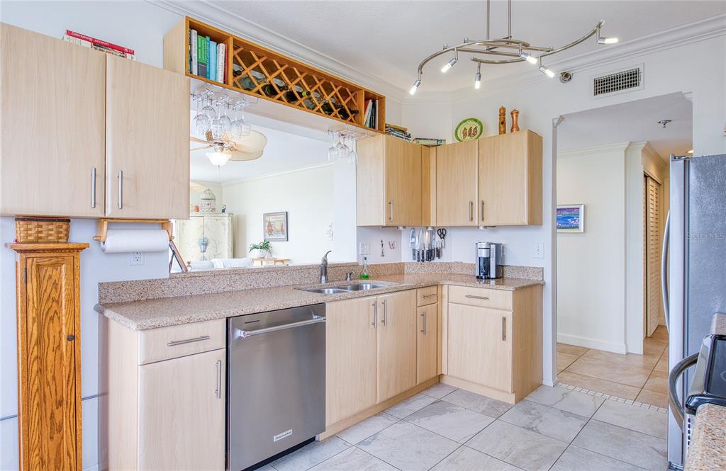 A kitchen features light wood cabinets, granite countertops, stainless steel appliances, and a wine rack — 7974 SAILBOAT KEY BOULEVARD S UNIT 301, SOUTH PASADENA, FL
