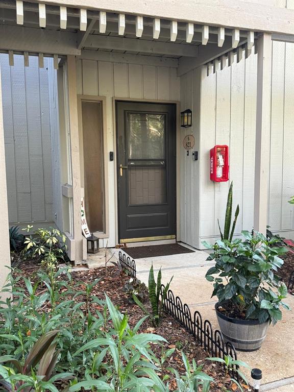 The exterior of a residential entrance features a dark door, a fire extinguisher, and landscaping — 821 PINEWOOD COURT UNIT 821, HAINES CITY, FL