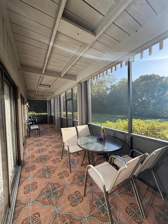 A screened-in porch features patterned tile flooring, a glass-topped table, and outdoor seating — 821 PINEWOOD COURT UNIT 821, HAINES CITY, FL