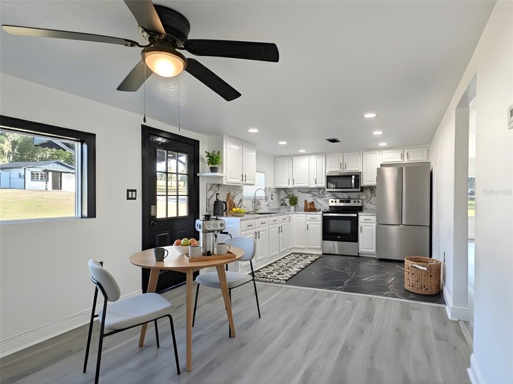 A kitchen and dining area features white cabinets, stainless steel appliances, and a black door — 15209 BAILEY HILL ROAD, BROOKSVILLE, FL