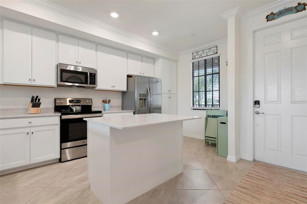 A kitchen features white cabinets, stainless steel appliances, a center island, and tile flooring — 17704 GAWTHROP DRIVE UNIT 205, BRADENTON, FL