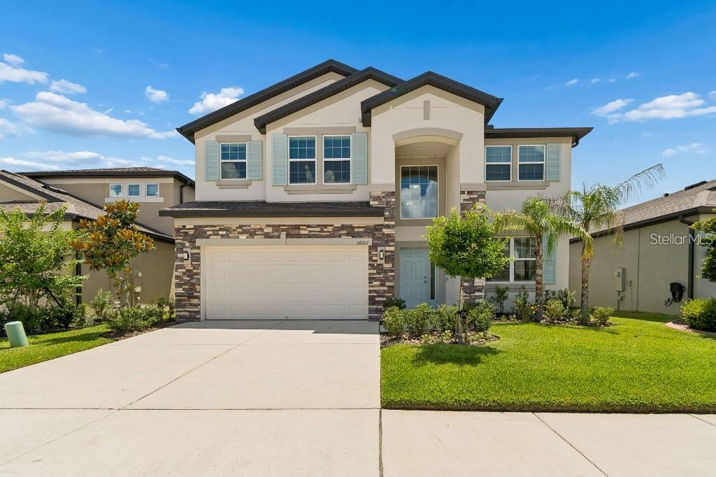 A two-story suburban house features a stone-accented facade, a two-car garage, and light-colored stucco — 16011 SONOMA GROVE CIRCLE, TAMPA, FL