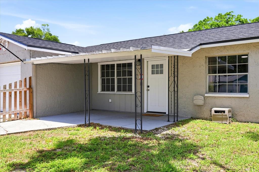 A single-story house exterior features a covered concrete porch, white front door, and metal supports — 2429 MARTHA LANE, LAND O LAKES, FL
