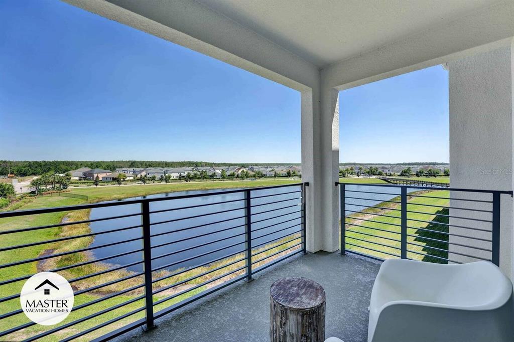 A covered balcony overlooks a pond and a residential neighborhood under a clear blue sky — 3191 PARADOX CIRCLE UNIT 405, KISSIMMEE, FL