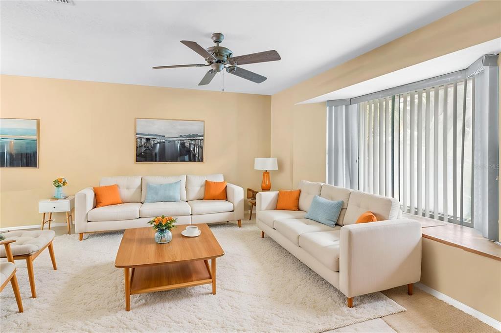 A living room features two cream sofas, a wooden coffee table, and a ceiling fan — 9212 RUSTIC PINES BOULEVARD W, SEMINOLE, FL