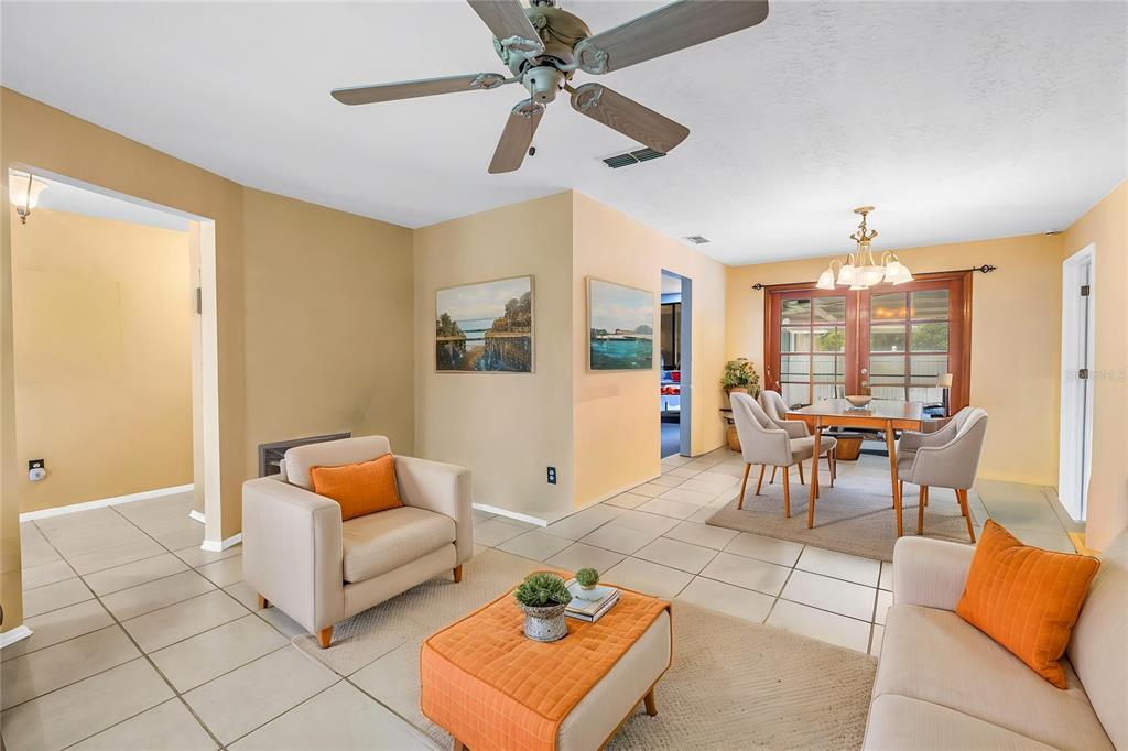 A living and dining area with tile floors, a ceiling fan, and orange accent pillows — 9212 RUSTIC PINES BOULEVARD W, SEMINOLE, FL